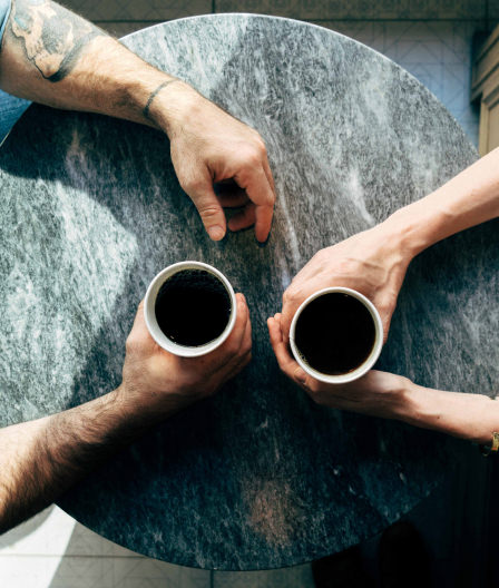 Top down view of a couple drinking coffee at cafe table