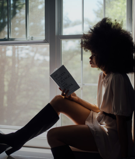 Woman reading a book next to a window