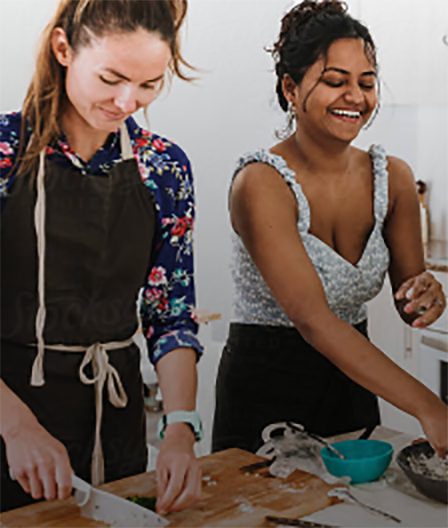 Two women preparing food with aprons on